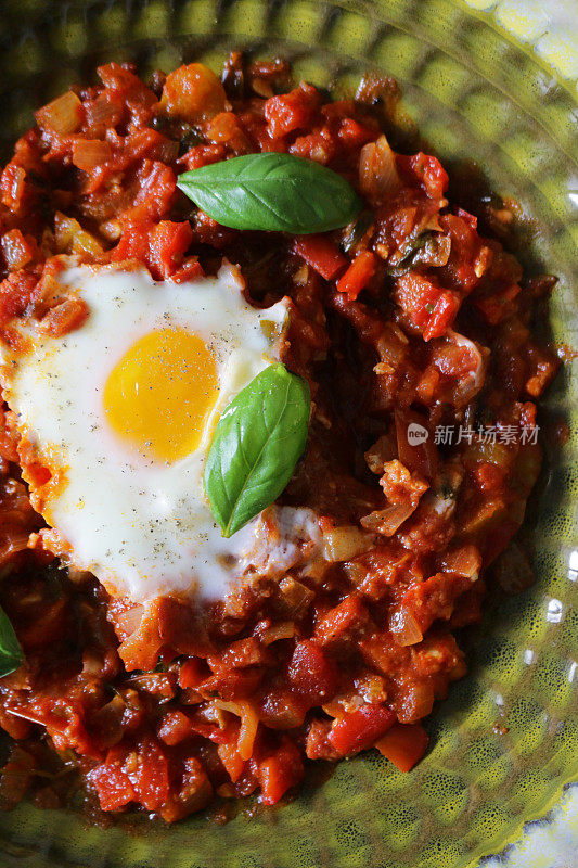 地中海健康早餐shakshouka / shakshuka / chakchouka在一个碗里，鸡蛋煮在西红柿，辣椒，洋葱，橄榄油，大蒜和罗勒酱里。用孜然、红辣椒和胡椒调味的调味汁，配面包食用。